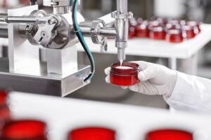 worker filling container with cream cosmetic factory
